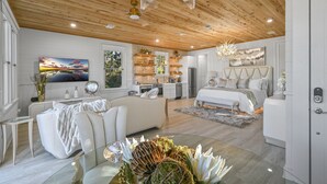 A modern, well-lit room with a wooden ceiling, a large bed, a dining area, and a kitchen. - ★Luxuriously Romantic One-Of-A-Kind Treehouse w/Canoe, Fire Pit and More★ (Santa Rosa Beach)