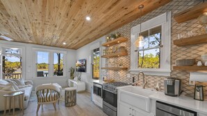 A modern kitchen with white cabinets, stainless steel appliances, and wooden ceiling beams. - ★Luxuriously Romantic One-Of-A-Kind Treehouse w/Canoe, Fire Pit and More★ (Santa Rosa Beach)