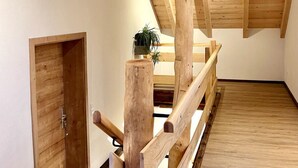 A wooden staircase with a handrail, a door, and a plant in the background. - Pure Allgäu. Beautifully renovated open penthouse. Apartment "Eva".  (Altusried - Frauenzell)