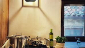 Une cuisine équipée d’une cuisinière à gaz, de casseroles, d’une bouteille d’huile d’olive et d’un pot de basilic.