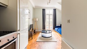 A modern kitchen with a stove, oven, and a dining table with a lamp. - The Chelsea Collection (London)