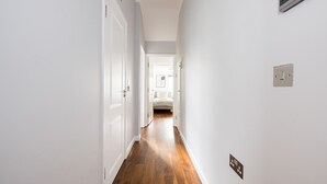 A narrow hallway with wooden flooring and white walls. - The Chelsea Collection (London)