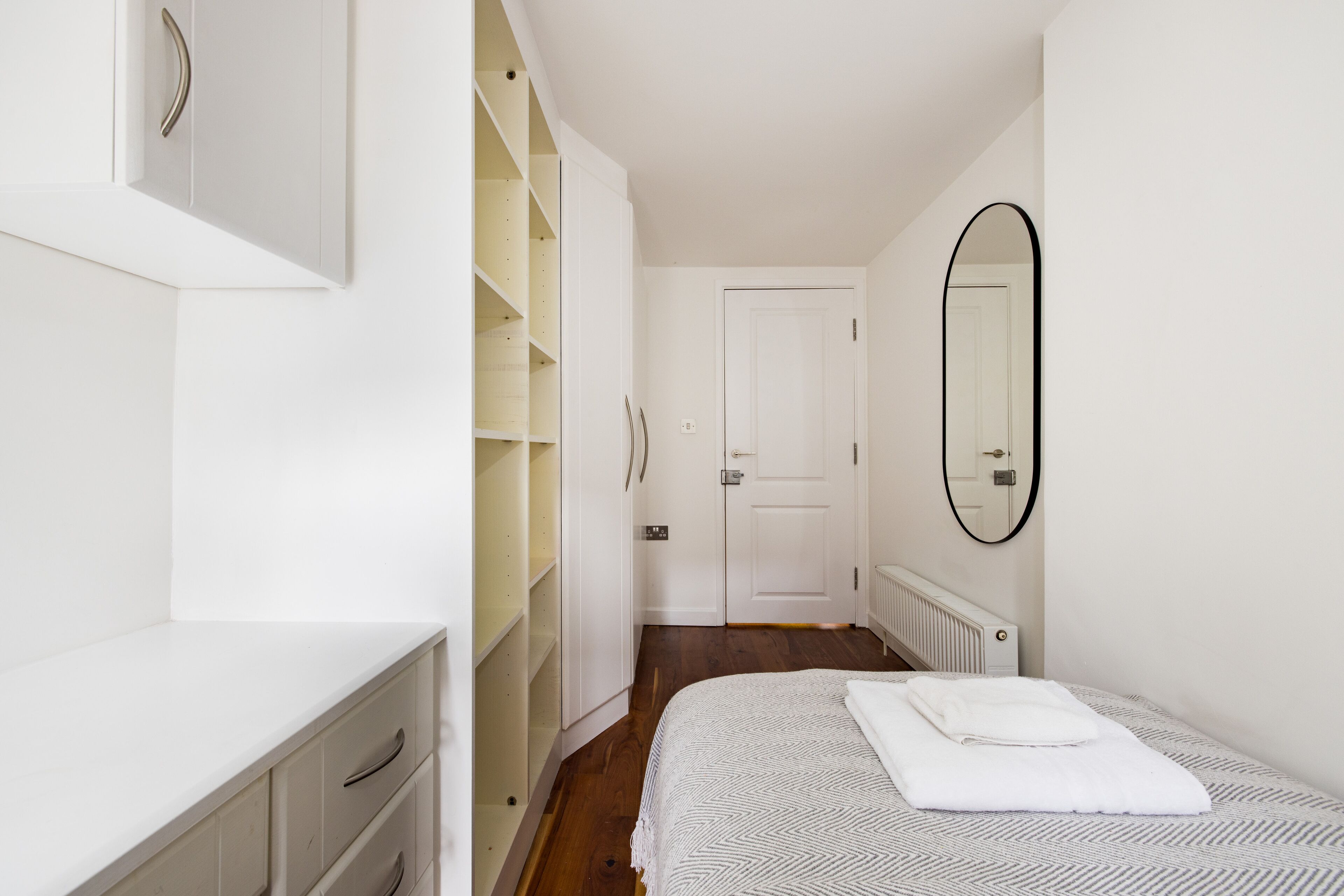 Een slaapkamer met een bed, een kledingkast, een spiegel en een deur.