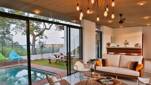 A modern living room with a pool, large windows, and a dining area. - Misty Villa by The Serendipity Collection (Ambagamuwa)