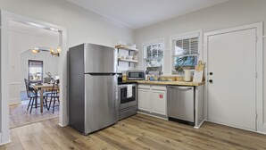 Una cucina moderna con elettrodomestici in acciaio inox, pavimento in legno e una finestra con persiane.