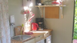 Una cocina compacta con un lavamanos, una cafetera y una pequeña encimera.