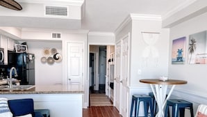 Una cocina moderna con armarios blancos, una isla central y taburetes azules.