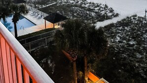 Vista de una playa con piscina, sillas de descanso y un edificio pequeño.