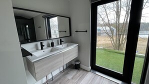 Un baño moderno con un ventanal grande, lavamanos doble y un espejo.