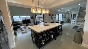 Una cocina moderna con una isla central, estanterías negras y lámparas colgantes.