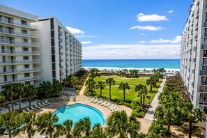 A resort with a swimming pool, palm trees, and a view of the ocean.