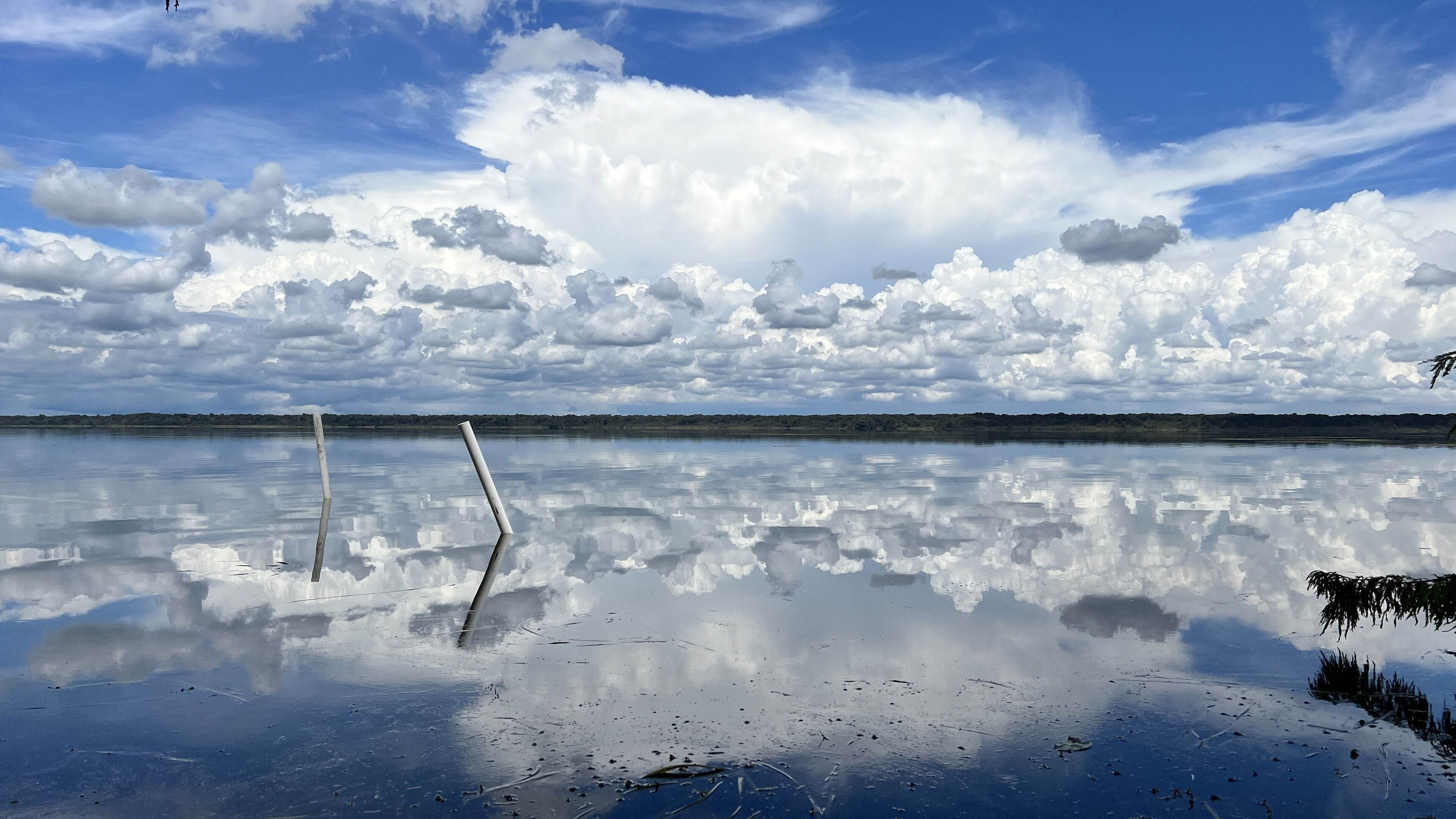 En stilla sjö med en tydlig spegelbild av himlen och molnen.