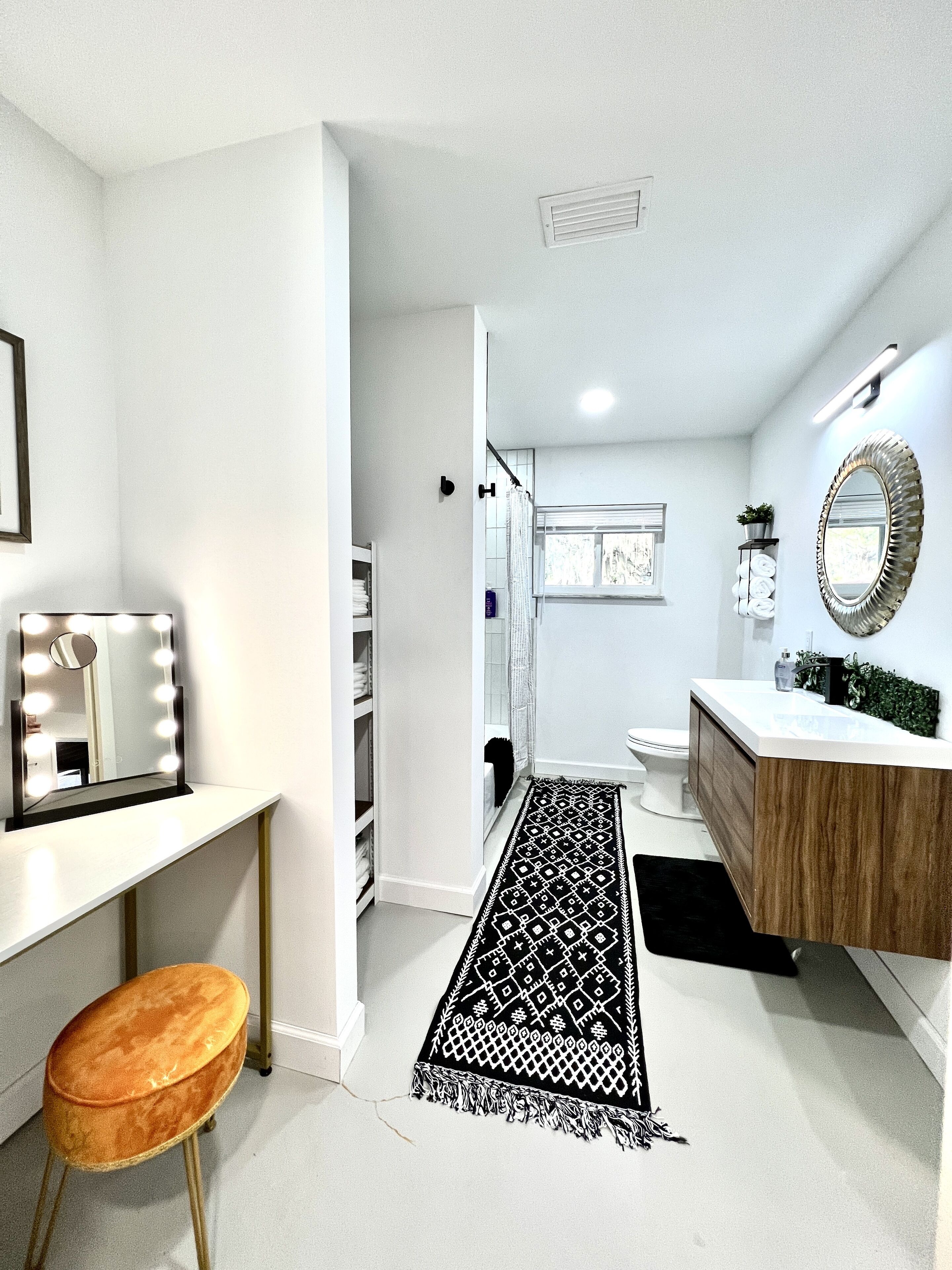 A modern bathroom with a vanity, mirror, and a black patterned rug.