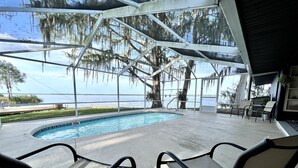 An indoor pool area with a view of the water, chairs, and a covered seating area. - Peaceful & stylish pool home with gorgeous lake views (Lake Panasoffkee)