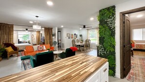 A modern living room with a wooden coffee table, a sofa, and a dining area with a white table and chairs. - Peaceful & stylish pool home with gorgeous lake views (Lake Panasoffkee)