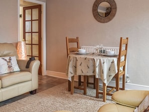 A dining area with a table set for four, a sofa, and a mirror on the wall.