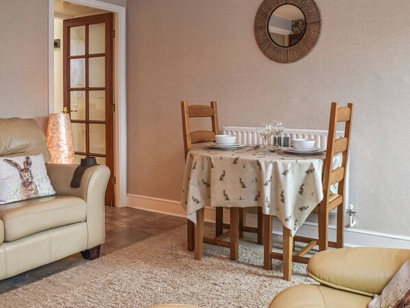 A dining area with a table set for four, a sofa, and a mirror on the wall.