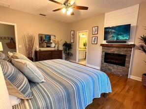 A bedroom with a bed, a fireplace, a TV, and a ceiling fan. - Gulf-access home with a 73ft dock (Crystal River)