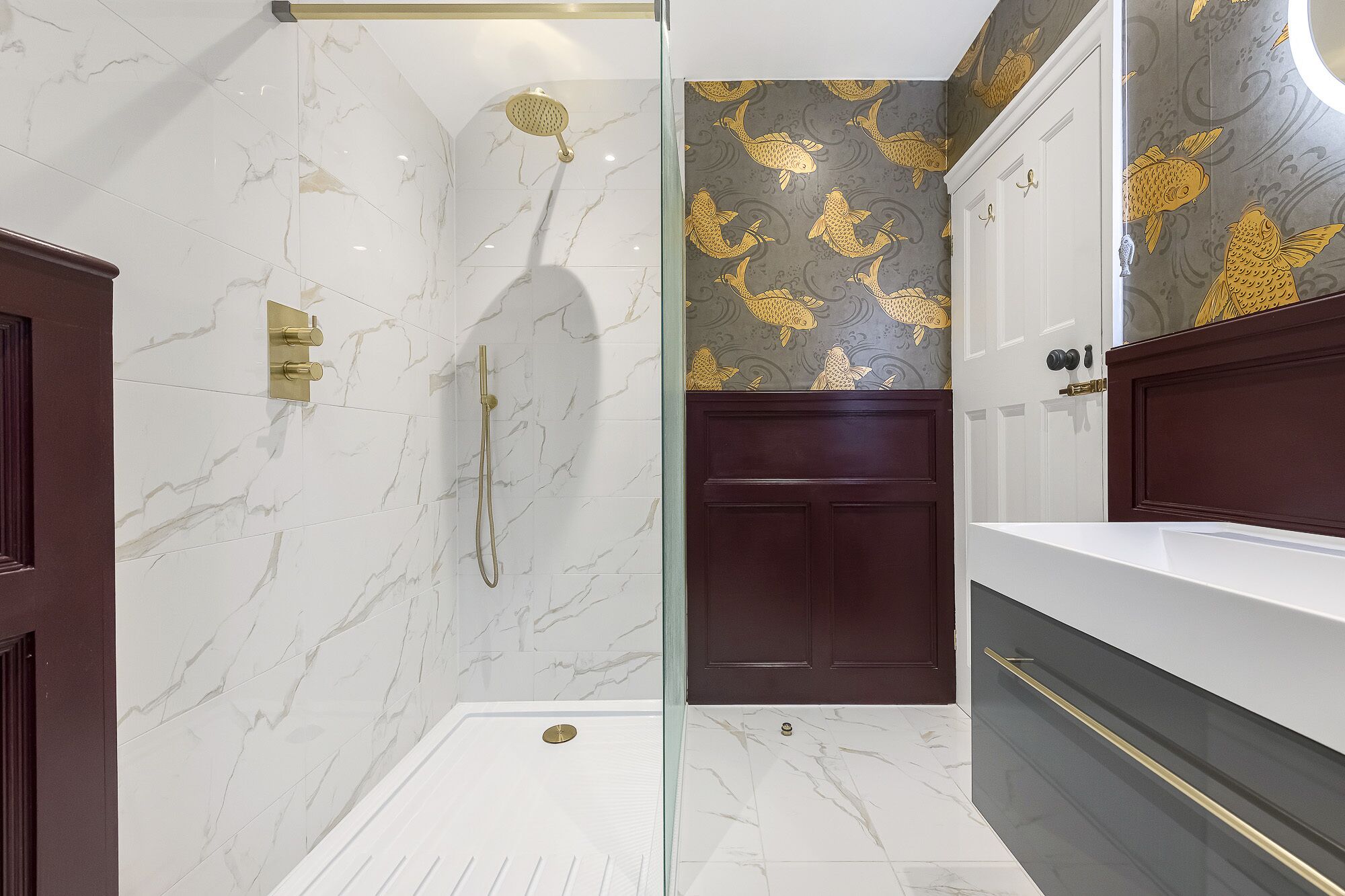 Une salle de bain moderne dotée d’une douche à parois de verre, de murs en marbre et d’un meuble-lavabo avec un meuble en bois foncé.