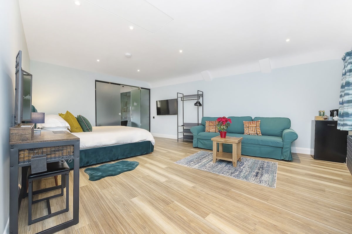 Quarto moderno com cama, escrivaninha, sofá e televisão.
