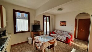 A compact living space with a kitchenette, a dining table, a sofa, and a TV.