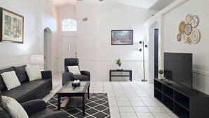 A modern living room with a sofa, armchair, coffee table, TV stand, and decorative wall art. - Wow! 3BDR Single-story home in Tempe/Chandler (Tempe)