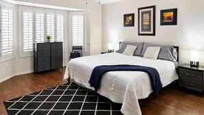 A bedroom with a bed, a dresser, a nightstand, a lamp, and a ceiling fan. - Pet-Friendly 3BR | King Bed | Fenced Yard (Tempe)