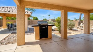 An outdoor patio with a barbecue grill, seating area, and a covered section. - Pet-Friendly 3BR | King Bed | Fenced Yard (Tempe)
