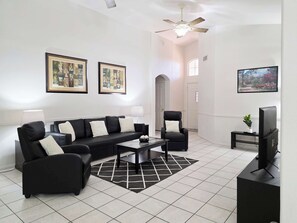 A modern living room with a black sofa, armchairs, a coffee table, a TV, and framed artwork on the walls. - Wow! 3BDR Single-story home in Tempe/Chandler (Tempe)