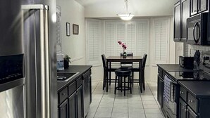 A modern kitchen with stainless steel appliances, a dining area with a table and chairs, and a tiled floor. - Wow! 3BDR Single-story home in Tempe/Chandler (Tempe)