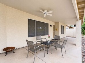 An outdoor patio with a table and chairs, a ceiling fan, and a view of a house. - Nice! 5 Bedroom Single-Story Chandler Home (Chandler)