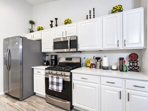 A modern kitchen with white cabinetry, stainless steel appliances, and decorative items on the countertop.