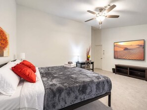 A bedroom with a bed, a ceiling fan, a desk with a chair, a television, and a painting on the wall. - Nice! 5 Bedroom Single-Story Chandler Home (Chandler)