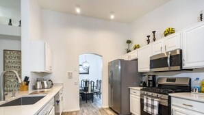 Une cuisine moderne avec des meubles blancs, des appareils en acier inoxydable et un plancher en bois.