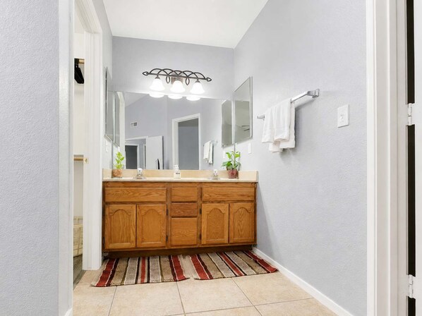 A bathroom with a wooden vanity, a mirror, and a light fixture above the mirror.