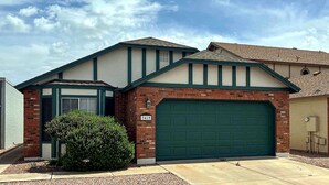 Une maison d’habitation avec un garage, un petit porche et une pelouse bien entretenue.