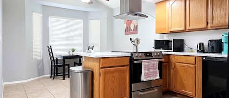 A modern kitchen with wooden cabinets, a stainless steel range, a microwave, and a dishwasher.