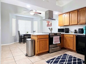 A modern kitchen with wooden cabinets, a stainless steel range, a microwave, and a dishwasher. - Pet-Friendly 3BR | Fenced Yard | King Bed (Chandler)