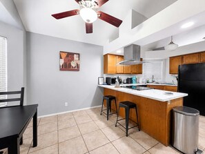 A modern kitchen with a central island, wooden cabinets, and a ceiling fan. - Pet-Friendly 3BR | Fenced Yard | King Bed (Chandler)