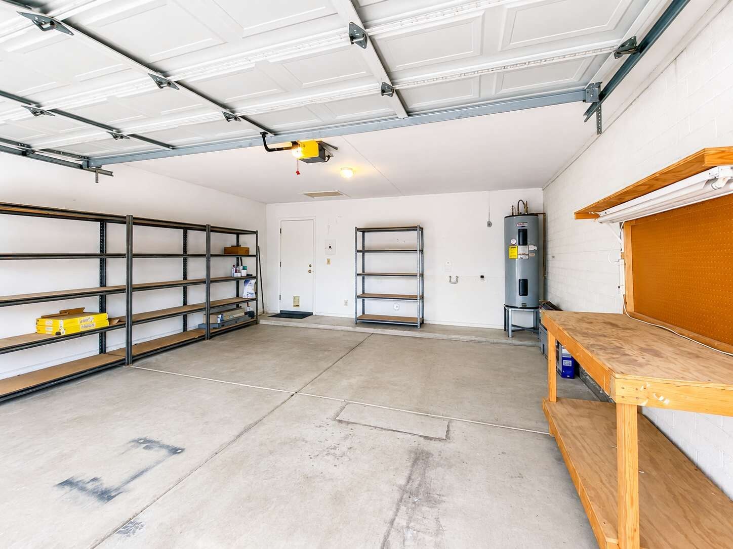 Eine Garage mit Metallregalen, einem Warmwasserbereiter und einer Holzwerkbank.