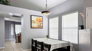 Un coin repas avec une table, des chaises et un tableau accroché au mur.