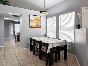 A dining area with a table, chairs, and a painting on the wall. - Pet-Friendly 3BR | Fenced Yard | King Bed (Chandler)