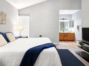 A bedroom with a bed, bedside table, lamp, and a view into the bathroom. - Pet-Friendly 3BR | Fenced Yard | King Bed (Chandler)