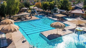 Une piscine dotée de plusieurs couloirs, de parasols et d’un élément décoratif aquatique.