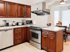 Una cocina con armarios de madera, estufa de acero inoxidable, microondas y lavavajillas.