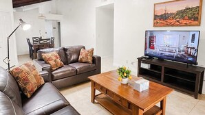 A living room with a leather sofa, wooden coffee table, and a television.