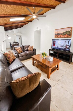 Una sala de estar con un sofá de cuero, una mesa de centro de madera y una televisión.