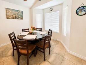 A dining room with a round table, four chairs, a vase with flowers, and a painting on the wall. - Wow! Single-story 3BR Chandler home (Chandler)