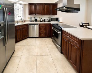 A modern kitchen with stainless steel appliances, wooden cabinets, and a tiled floor. - Wow! Single-story 3BR Chandler home (Chandler)