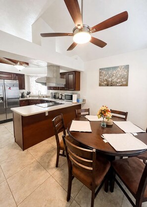 A modern kitchen with a central island, dark wooden cabinets, stainless steel appliances, and a ceiling fan. - Wow! Single-story 3BR Chandler home (Chandler)